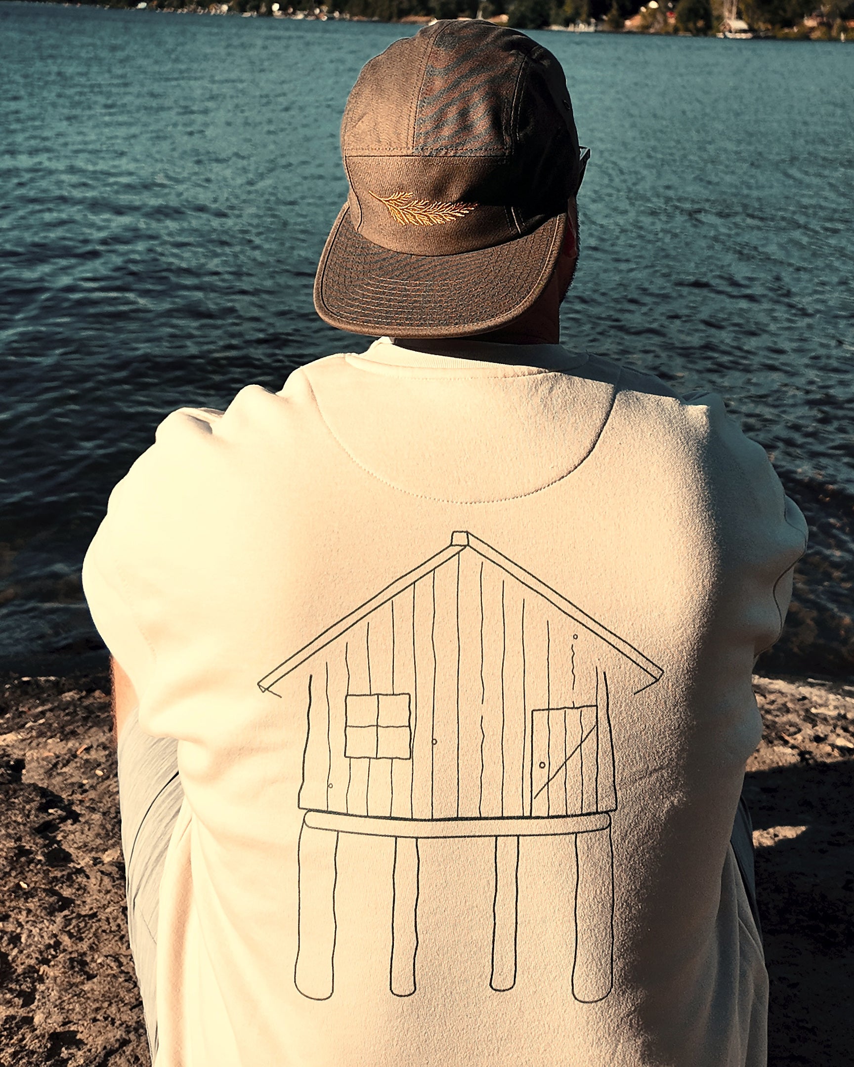 The Cabin Crew in bone by the lake, hand-drawn cabin printed across the back